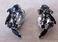 Front view showing black marquise and round faceted stones, hand prong set in rhodium plated metal, symmetrical design for left and right ears.