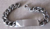 Top view of silver curb link bracelet with smooth engraving plaque and lobster claw clasp