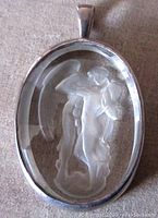 Front view of the oval carved clear glass pendant set in sterling silver showing the mythology man and woman intaglio scene.
