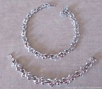 Full view of the vintage jewelry set with necklace and bracelet laid flat showing bow motif links.