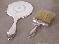 Front side of hand mirror and clothes brush showing polished silver, monogrammed 'B' on mirror back, and pale brush bristles