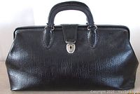 Front view showing textured leather, metal lock, and handle of the doctor bag.