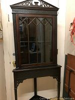 Front view of the entire cabinet showing carved pediment and glass door with muntin pattern