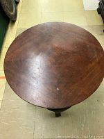 Top view of the round wooden table top, showing the pie-shaped veneer pattern and surface wear.