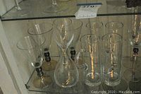 Front view showing martini glasses, beer mugs, shot glasses, and wine decanter on shelf.