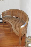 Full view of the peanut shaped wood bench showing the curved seat and backrest design.