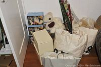 Photo of bags, boxes, teddy bears, and rolls of wrapping paper including boxes of mini lights