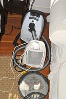 Photo showing all three items: a Miele vacuum cleaner canister with hose, the Honeywell heater in front, and the iRobot Roomba on the floor.