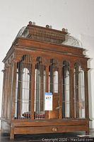 Wooden cage with metal bars and arched windows visible from the front view