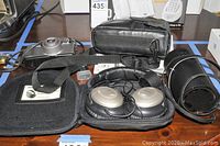 Overview photo of the Bose headphones, Canon camera, carrying cases and straps on a wooden surface.