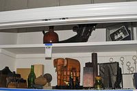 Shelf showing various carved wooden items, bottles, and decor with a large wood elephant central