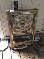 Full view of yellow vintage pachinko machine with convex glass playfield window and ball release lever at bottom right