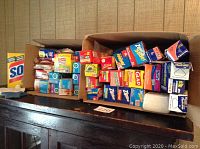 Photo showing various boxes of plastic storage and trash bags including Glad, Ziploc, Hefty, Reynolds, Tops, and others arranged in two cardboard boxes.