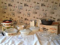 Full view of lot showing 2 Fire King covered casseroles with different decals, Corning Ware Spice of Life cookware, cast iron Dutch oven with packaging, glass casserole lids, Austria Email enamel casserole, and Sunbeam can opener.