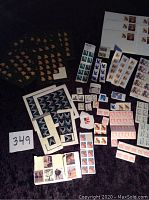 Wide view of multiple sheets and individual stamps laid out on a dark surface including colorful butterfly designs, flags, animals, and historical personages.