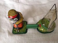 Top and side views of vintage tin golfer toy showing colorful golfer figure and putting green with net