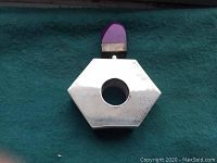 Top view of hexagonal silver perfume bottle showing shiny but slightly tarnished surface and the hole for the cap.