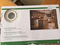 Photo of box showing part of the kit, a 4 inch white gimbal pot light trim and a kitchen lighting setup image.
