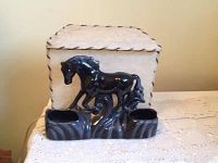 Front view of the black ceramic horse lamp on a table, showing glossy finish and two recessed holders.