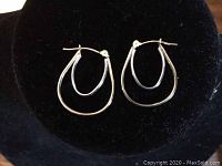 Photo of a pair of 14k white and yellow gold double hoop earrings on black velvet background.