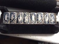 Front view of vintage Siam silver link bracelet showing detailed embossed figures on each link against black background with decorative silver edges.
