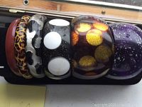 Top view showing all six bracelets stacked, highlighting various colors and patterns including solid brown, leopard print, black and silver, black with white polka dots, black with orange/gold dots, and purple with speckles.