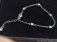 Full view of the sterling silver anklet laid out showing chain and cubic zirconia settings.