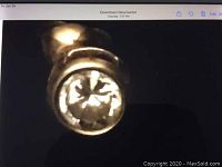 Close-up front view of gold stud earring with clear faceted stone in bezel setting