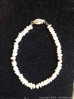 Full view of the freshwater pearl bracelet showing pearls and 14k gold clasp with maker's mark, against a black background.