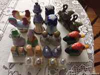 Photo showing multiple vintage salt and pepper shakers in various ceramic designs including roosters, ducks, people figures, and glass shakers.