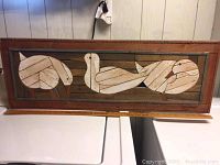 Wide shot of the full wood folk art panel, showing three stylized birds in lath art style within a wood frame, with a ruler at the base for scale.