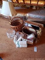 Shows the four wicker baskets including a picnic basket, the brass lamp with fabric shade, the clear glass candy dishes, paper candle cups and the wooden sleigh.