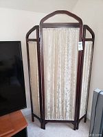 Full view of three-panel wooden privacy screen with beige floral fabric inserts, showing overall condition and size.
