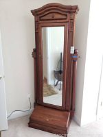 Full view of the wooden dressing mirror showing the arched top, full-length mirror, and base storage drawer.