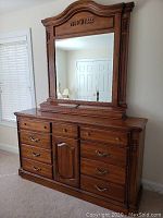 Full view of the two-piece set: hardwood dresser with drawers and cabinet base and the large attached mirror showing detailed wood work and brass handles, placed in a bedroom environment.