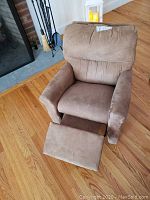 Front view of child's recliner chair with footrest extended, showing brown suede-like fabric and minor soiling.
