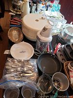Photo showing a white food dehydrator, a Bravetti quad blade mixer, various pans, a decorative plate, and some additional kitchenware items including measuring cups and a shell-shaped bowl.
