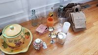 Photo showing the large yellow and green covered urn on matching large bowl, maroon and green covered urn, six assorted vases, pink stone jewellery box, English tea tin with tea, large glass fruit bowl, and a bundle of paper shopping bags.