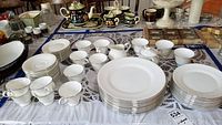 Full set of white Wedgwood Silver Ermine bone china dinnerware displayed on table including plates, cups, saucers, sugar bowl, creamer, and tongs.