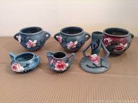 Full lot view showing all six pieces including three urn style vases, tall handled vase, creamer, and small bowl, all with floral decorations.