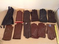 Top view of all 12 pairs of gloves arranged on a surface showing gloves of black, brown, and gray leather.