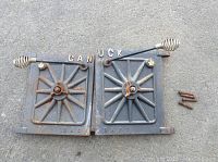 Full view of both cast iron stove doors placed side by side on the ground, showing design and condition.