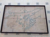 Full view of framed antique map showing blue water bodies forming lakes and islands along with black printed geographical names and details.