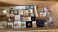 Boxes and trays with assorted costume jewelry including necklaces, bracelets, earrings, and brooches