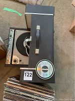 Top view of General Electric model 300 record player with vinyl records stacked below it, plus an RCA CD on top of the player.