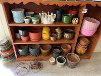 Full view of wooden bookshelf filled with a variety of plant pots and trays.