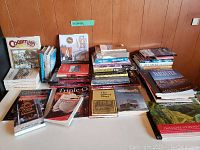 Wide shot of multiple stacks of books on a table, various titles related to Vancouver and Lower Mainland history, guides and culinary books.