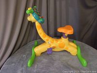 Side view of the yellow giraffe ride-on bike with green rockers, orange seat, and interactive handlebar