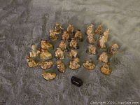 Overview of all 28 Wade figurines arranged on soft surface, including multiple human and animal figures and black sheep