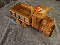 Side view of handcrafted wooden dump truck showing the cargo bed and painted decorative details on the side panels.